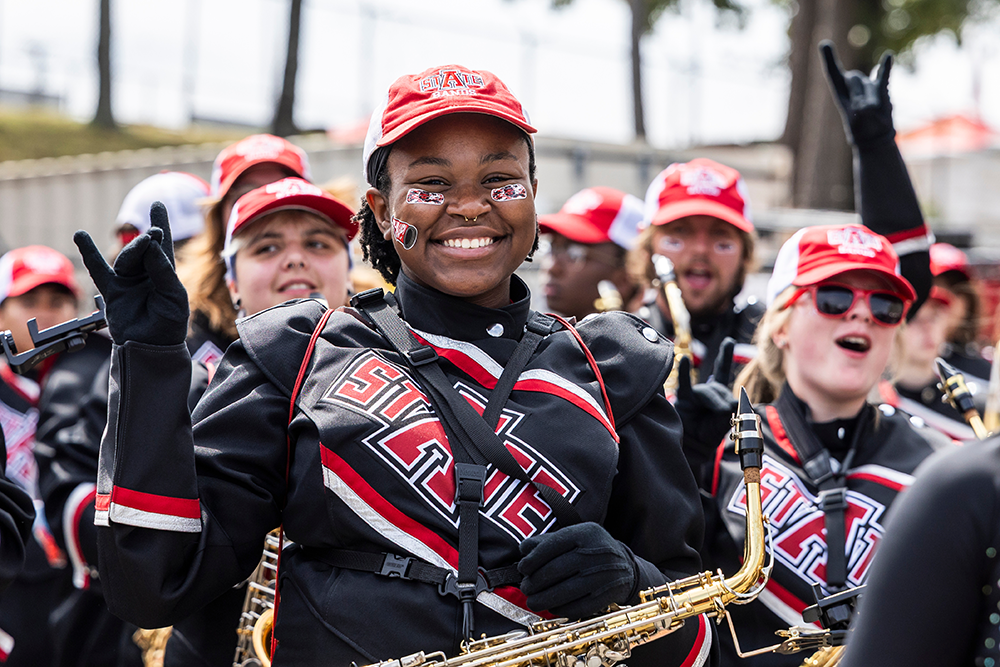 A member of the A-State band giving a Wolves Up.