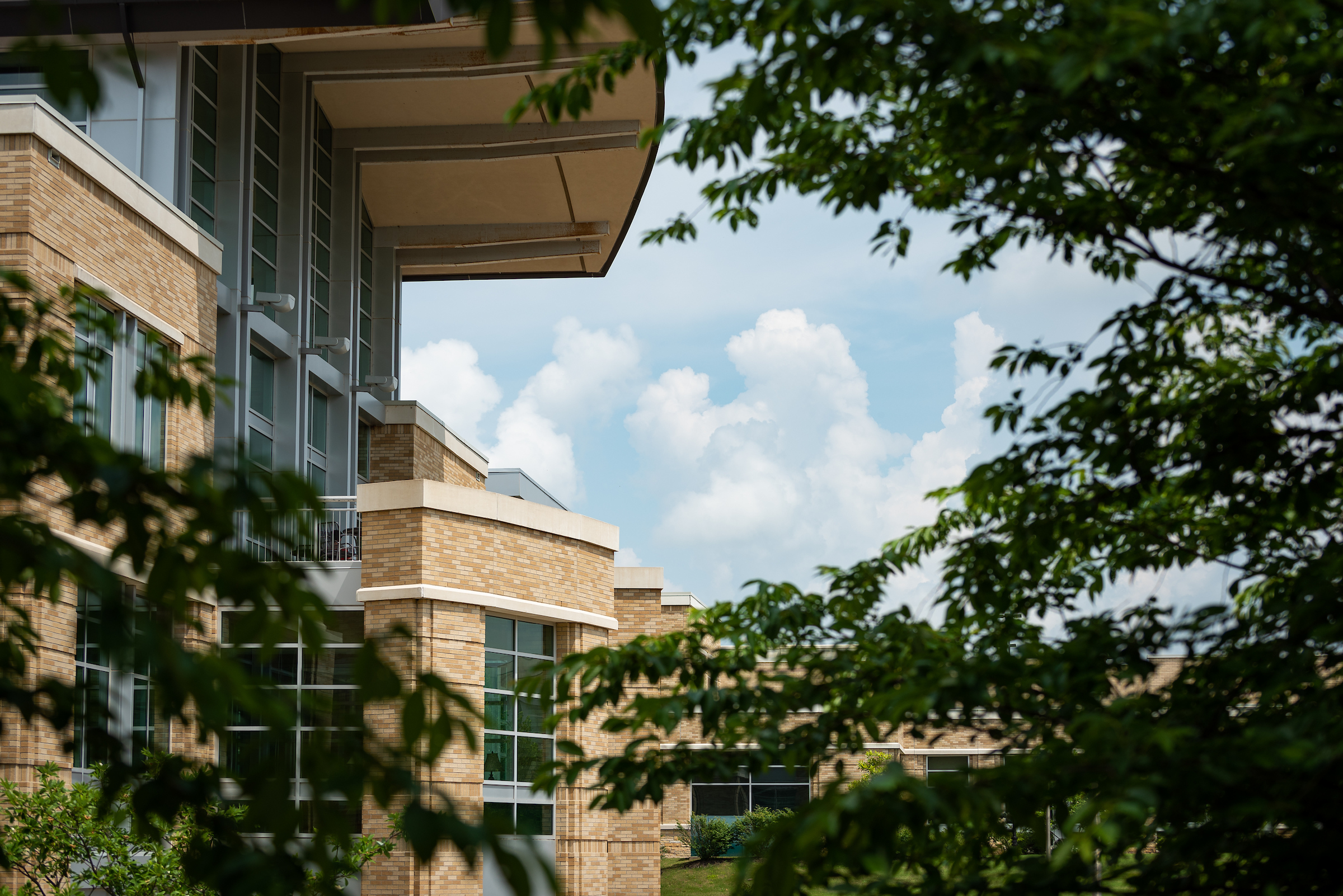 A-State campus building with brick exterior and large windows framed by trees.
