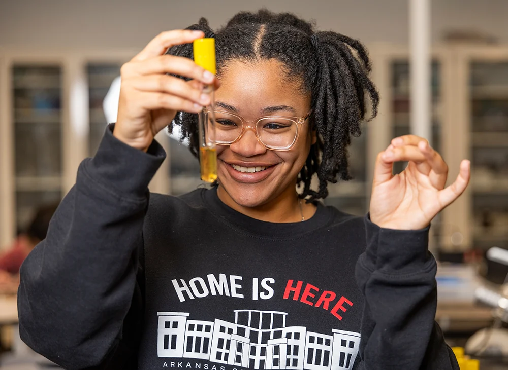 Student holding up a test tube and smiling.