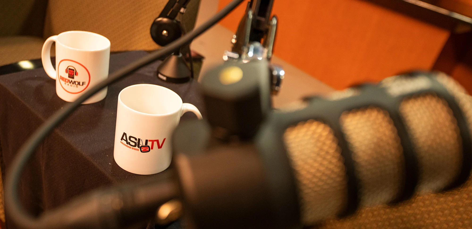 Two microphones and coffee cups brandishing the ASU-TV logo.