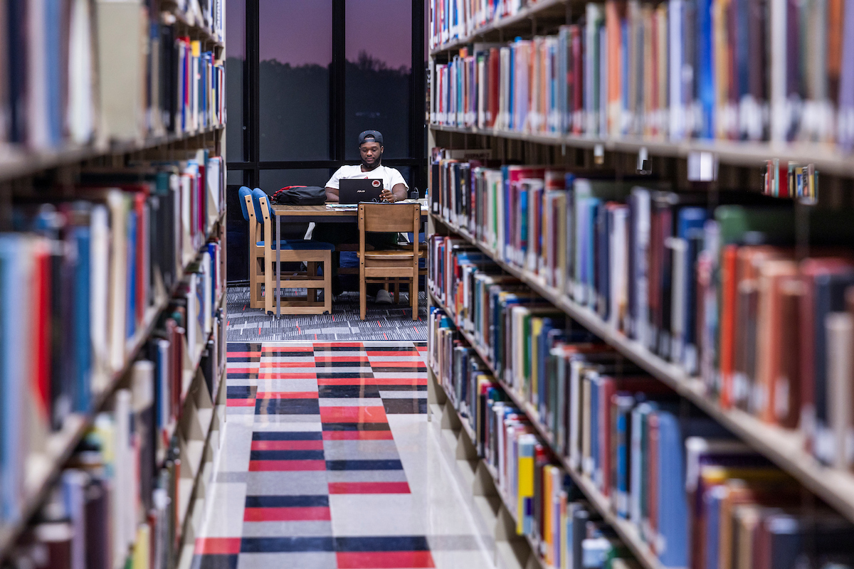Student studying among shelves of library books.