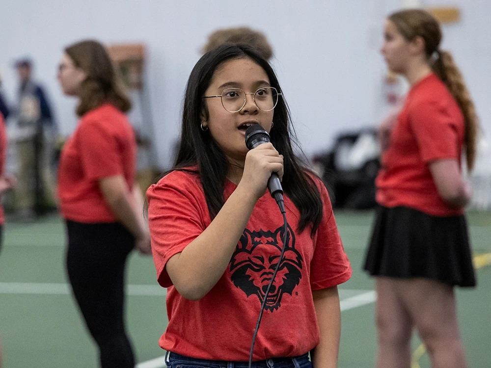 A student singing the National Anthem.