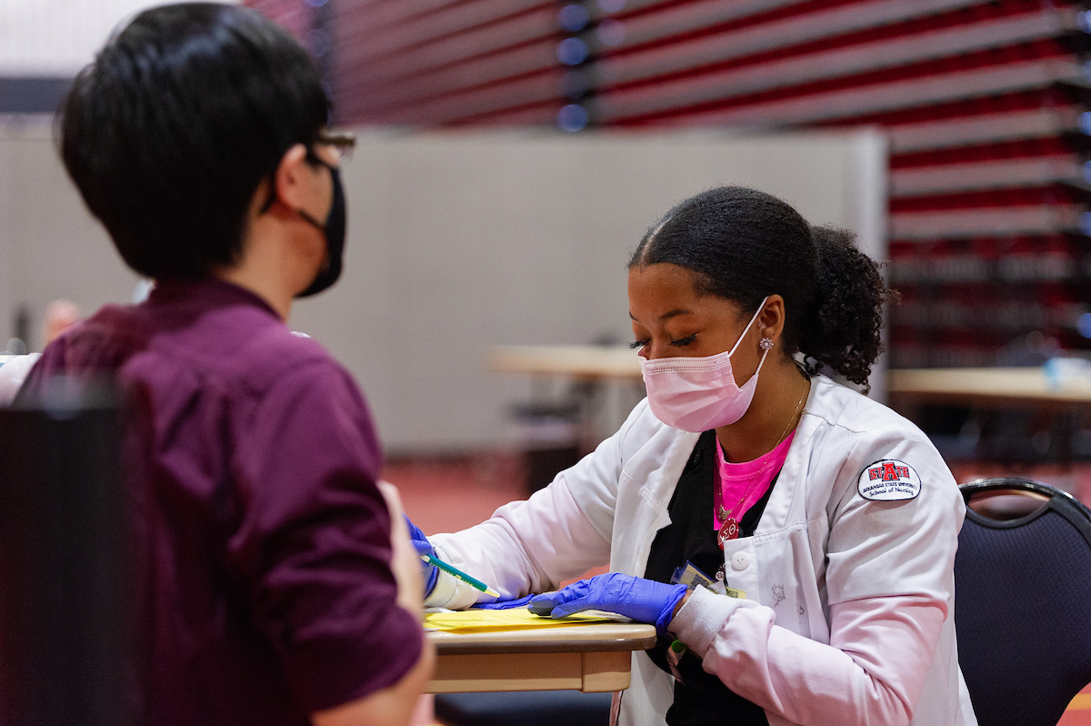 An A-State nursing student processes an international student during a flu vaccine clinic on campus.