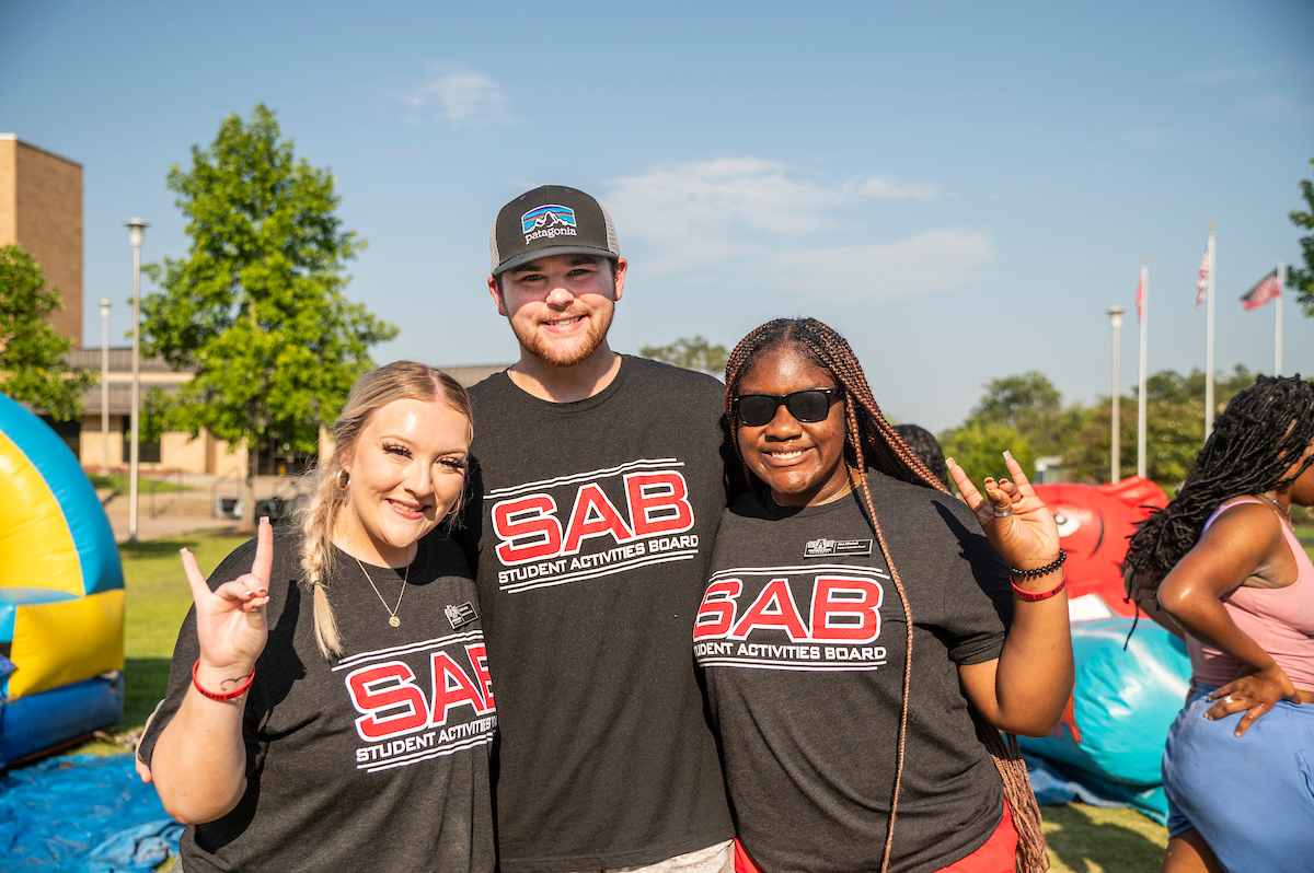 Student Activities Board members pose in matching SAB shirts during a campus event on a sunny day.