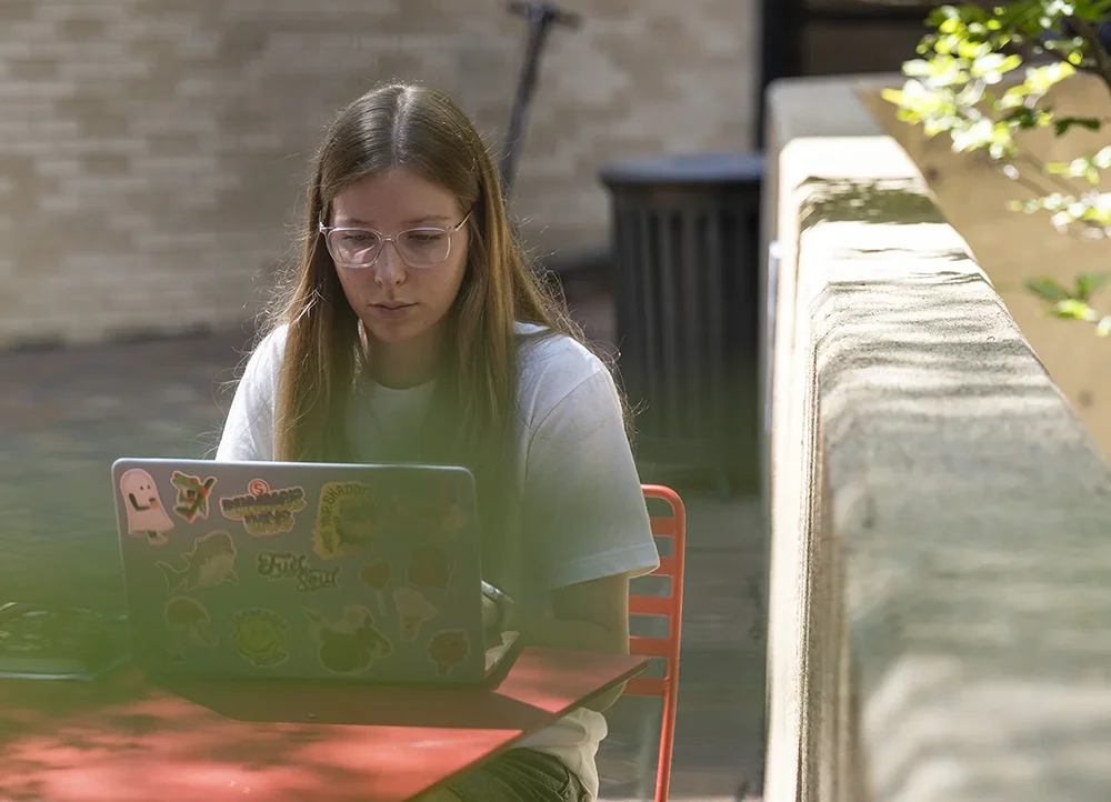 Student using laptop outside.