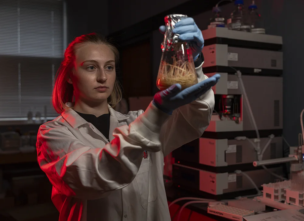 A student looking at a beaker of roots.