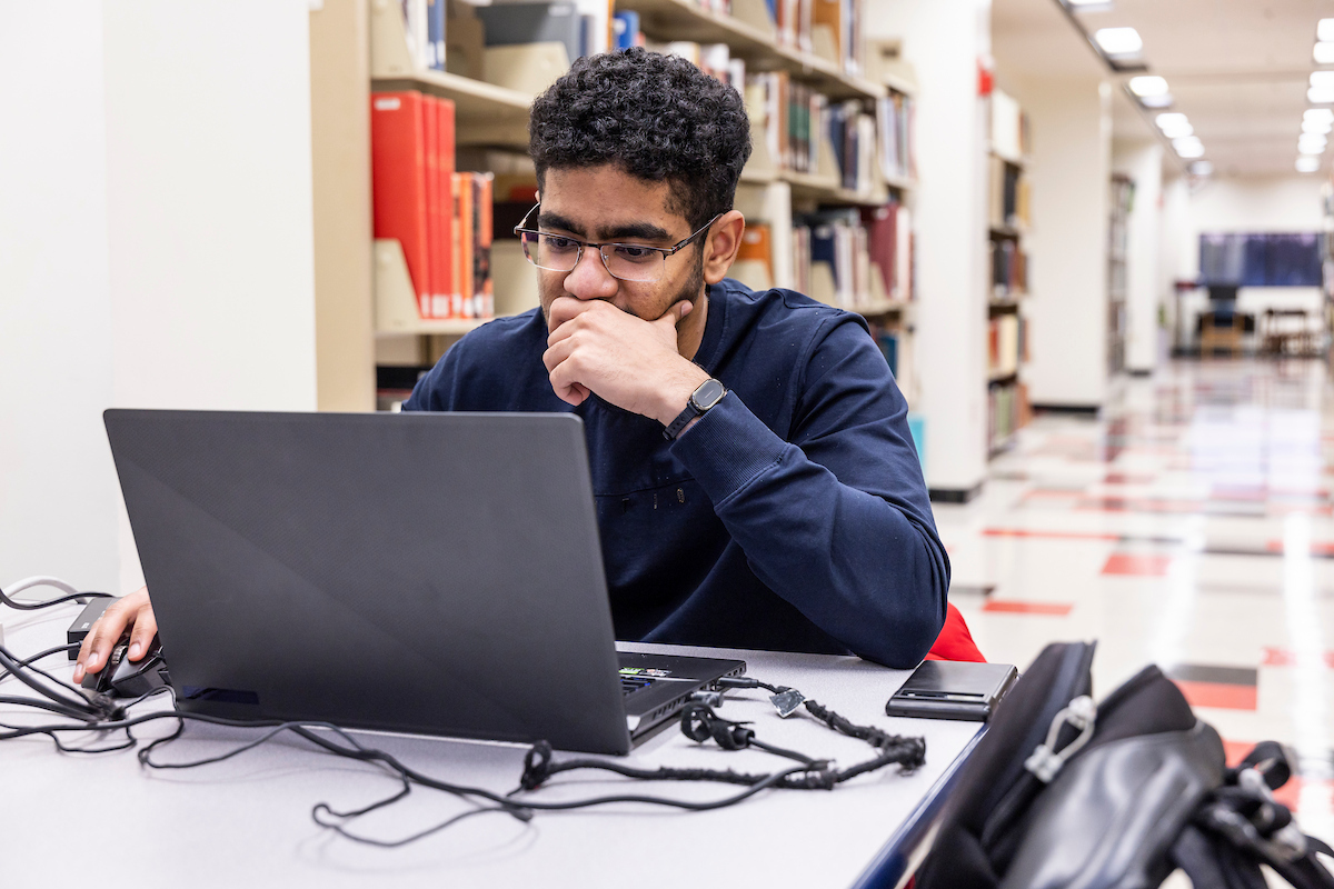 An A-State student in the library working on his laptop.