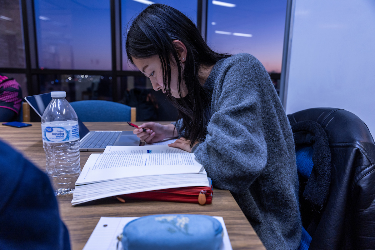 Student studying a textbook in the evening on campus.