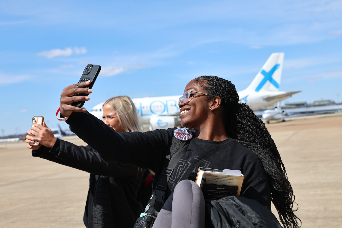 Students taking selfies outside of a plane.