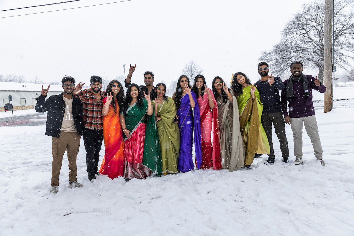 A-State students pose in colorful traditional clothing during a snowy winter day on campus.