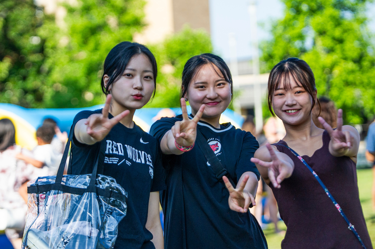 Three students holding up peace signs.