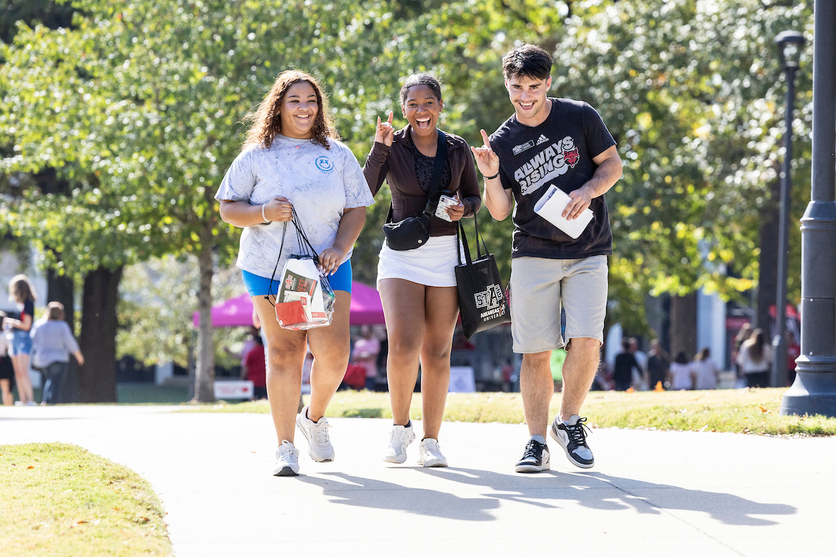 Three students giving a Wolves Up.