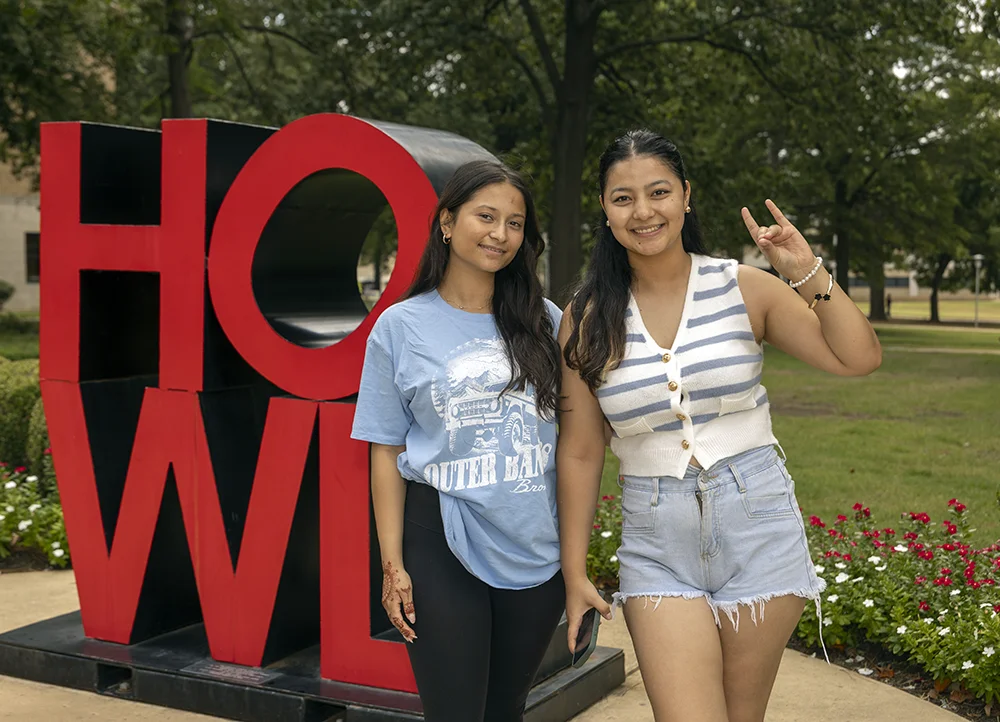 Two students posing next to the HOWL sculpture