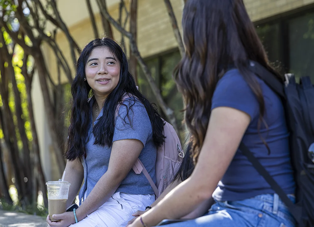Two students talking outside on campus.