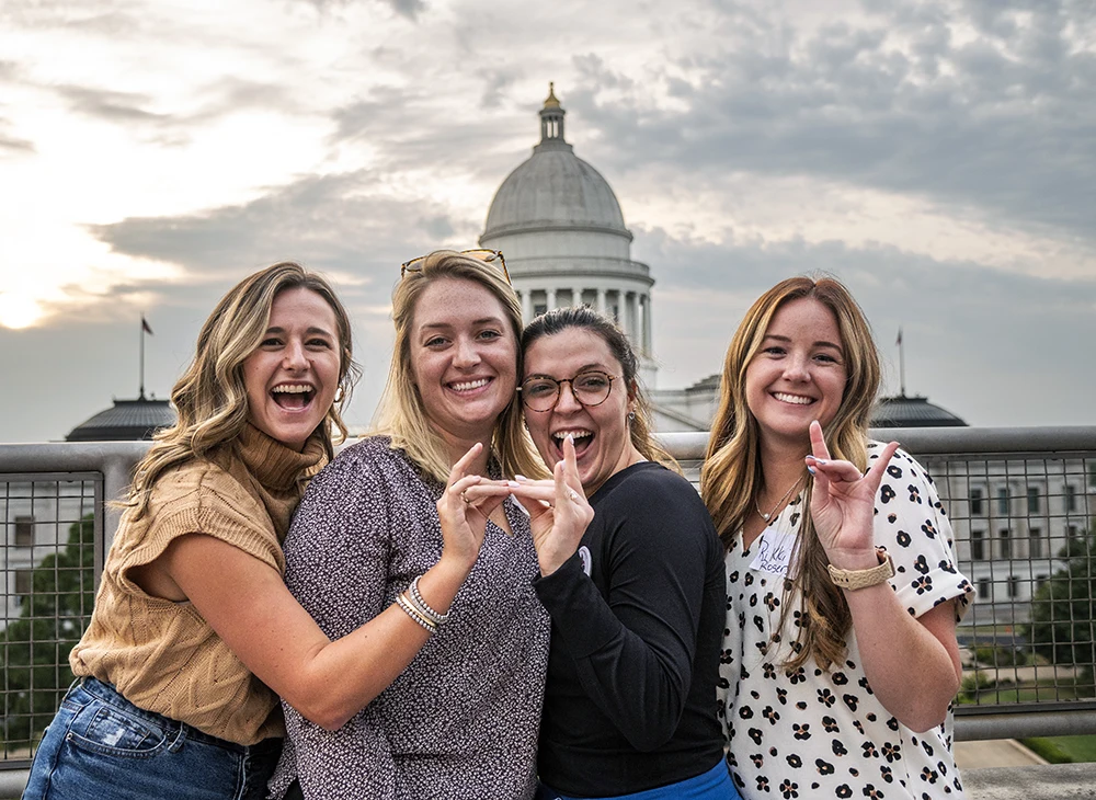 Group of women giving a Wolves Up at the capitol in Little Rock.