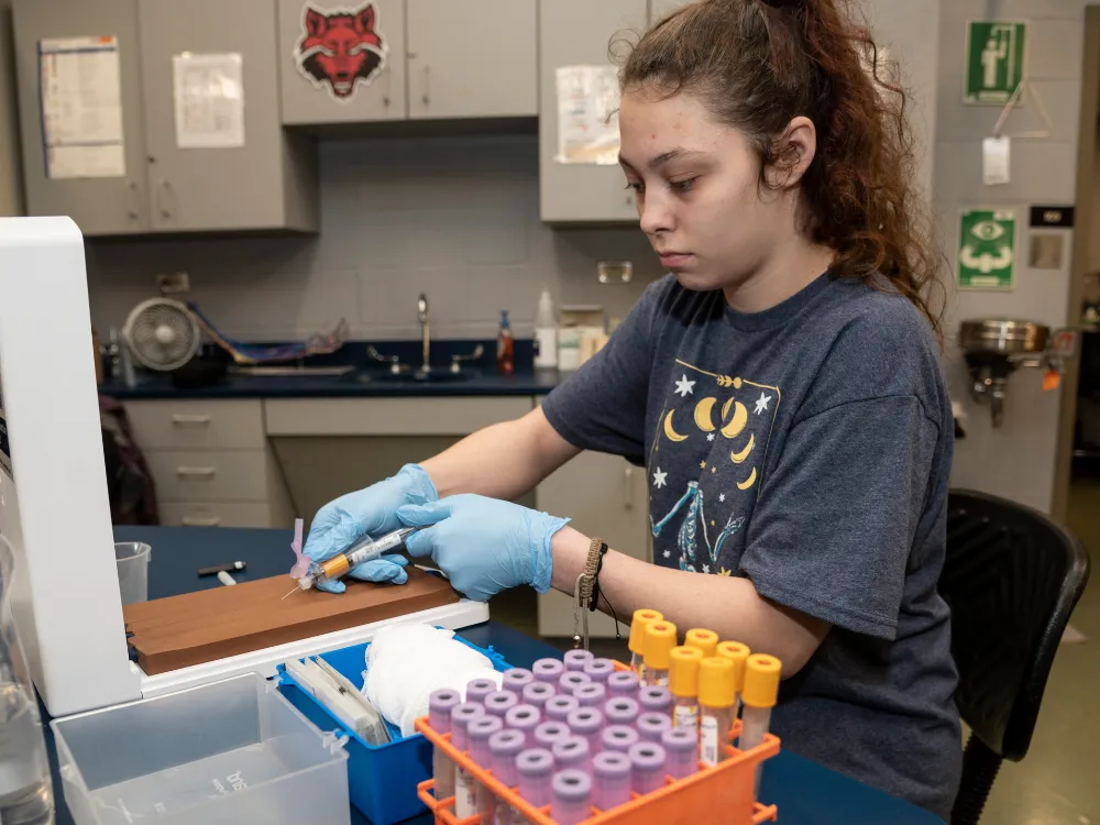 A-State student and professor hugging at the white coat ceremony after graduation.