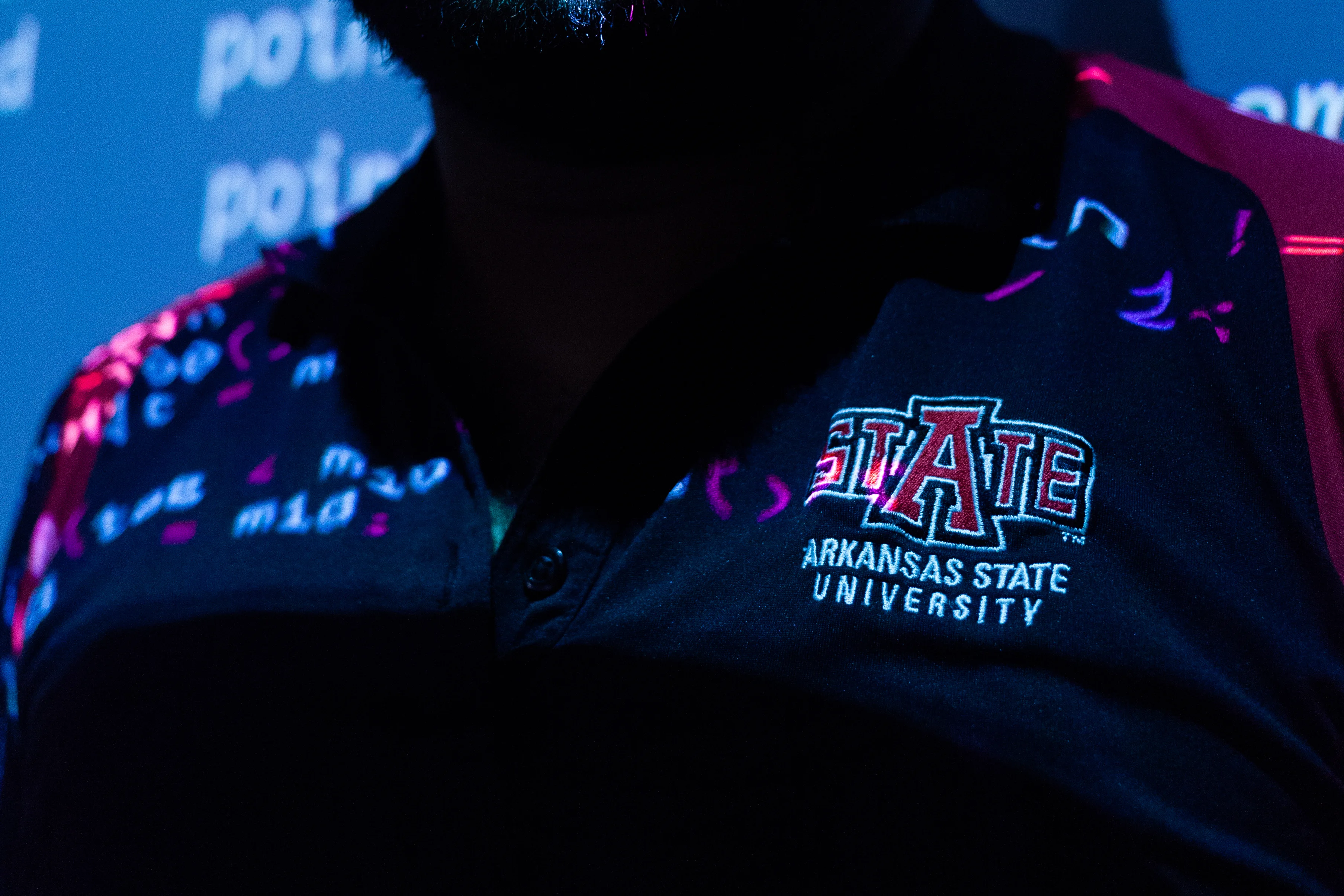 A-State logo shirt standing in front of a projector, projecting code.