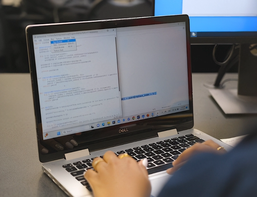 A-State student and professor going over lesson in front of class while they point at the projector.