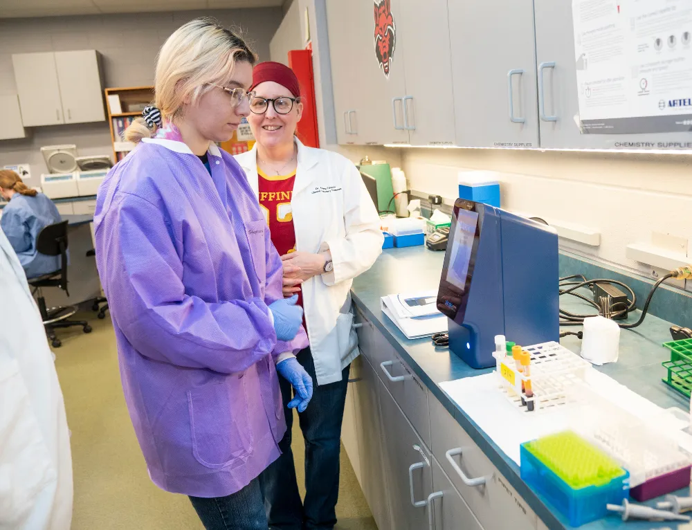 Student using centerfuge with blood samples in a hands on lab.