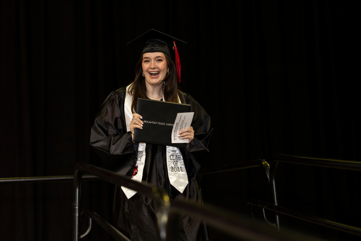 A recent graduate proudly displays her diploma cover at an A-State commencement ceremony.