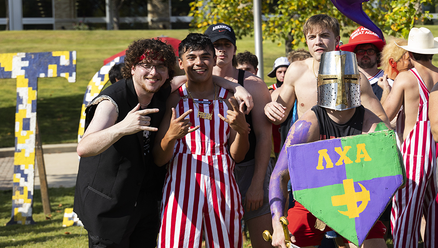 Fraternity members posing in funny costumes at Fraternity Bid Day celebration.
