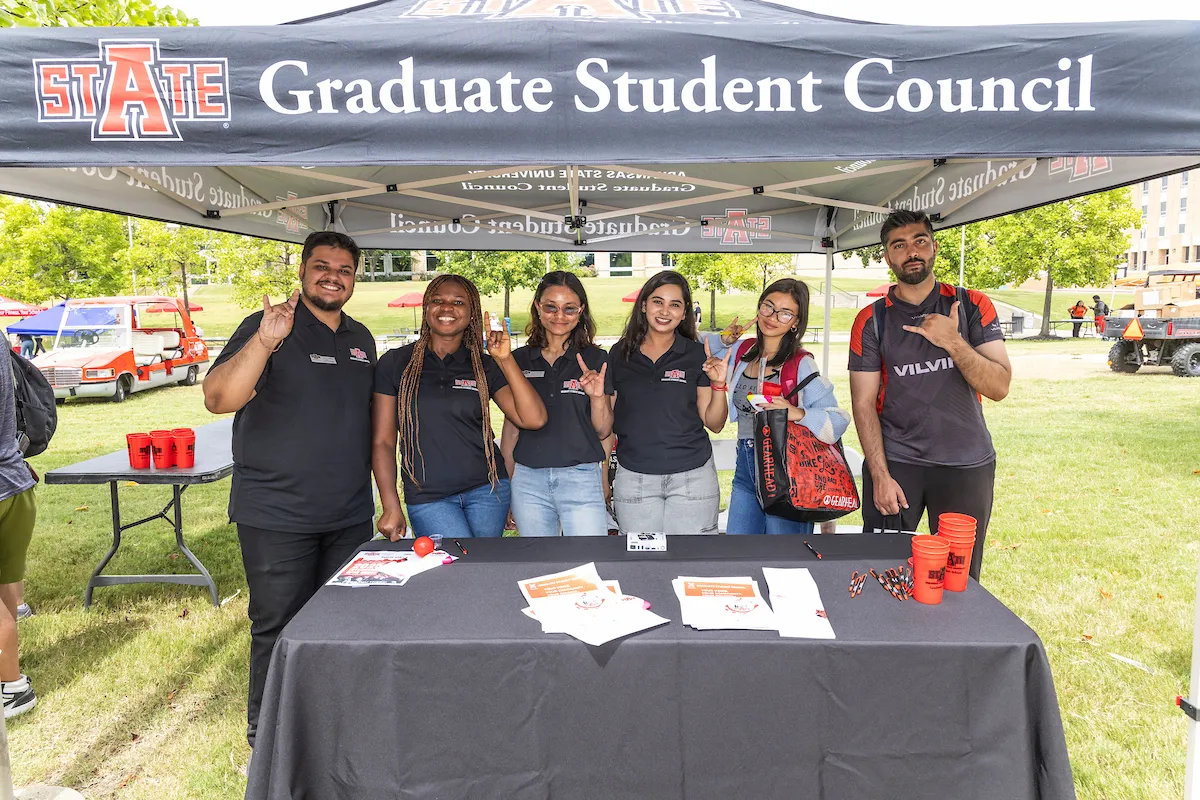 Members of the Graduate Student Council pose in front of an informational tent.