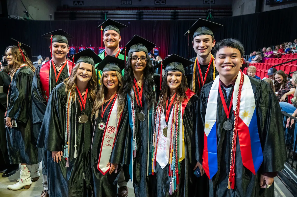 A group of smiling students takes a photo at a recent commencement ceremony.