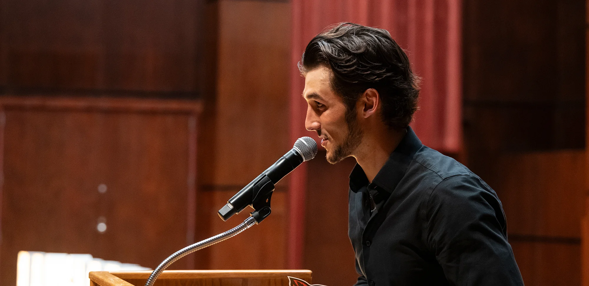 Speaker in auditorium with Red Wolves sign on podium.