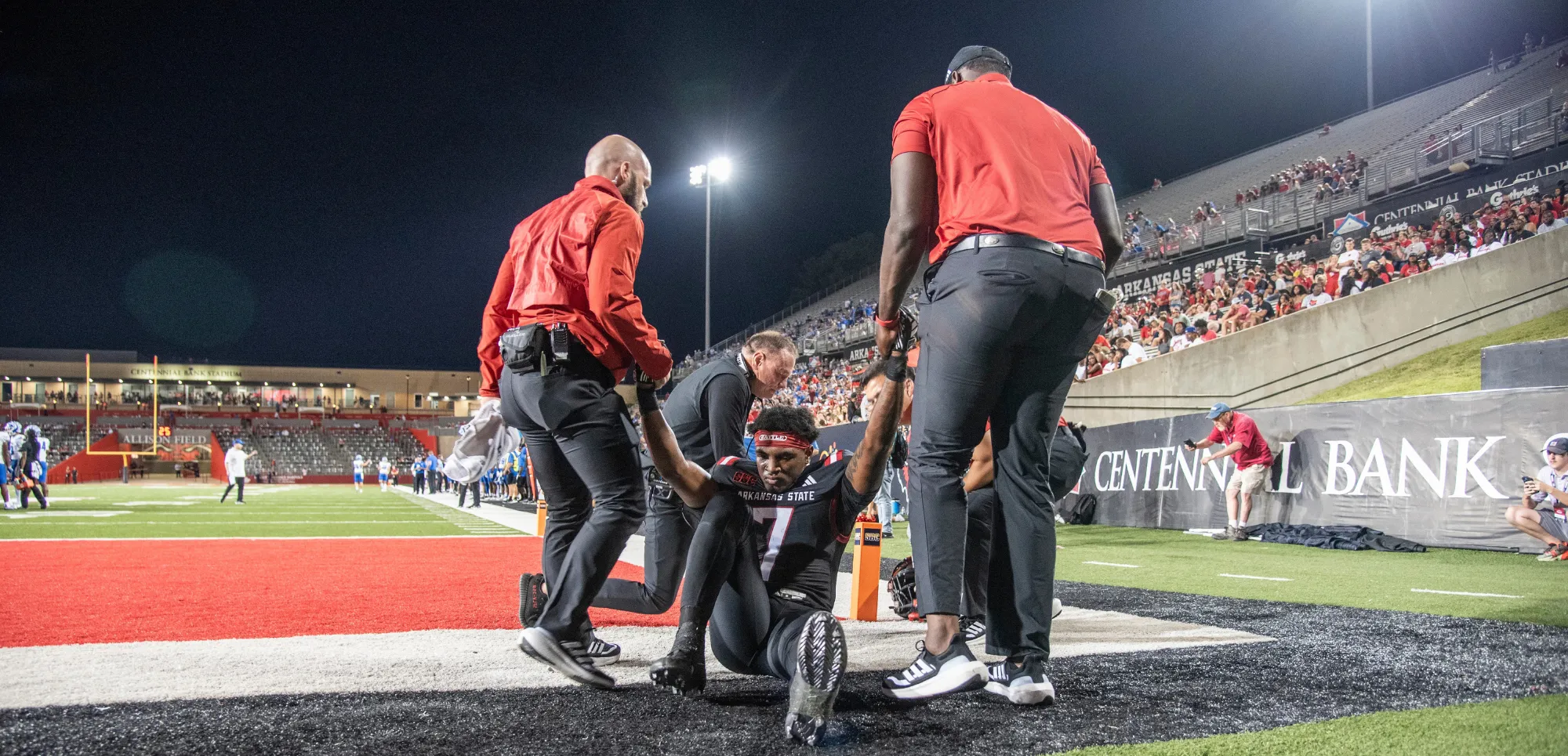 athletic trainers helping football player off of field.