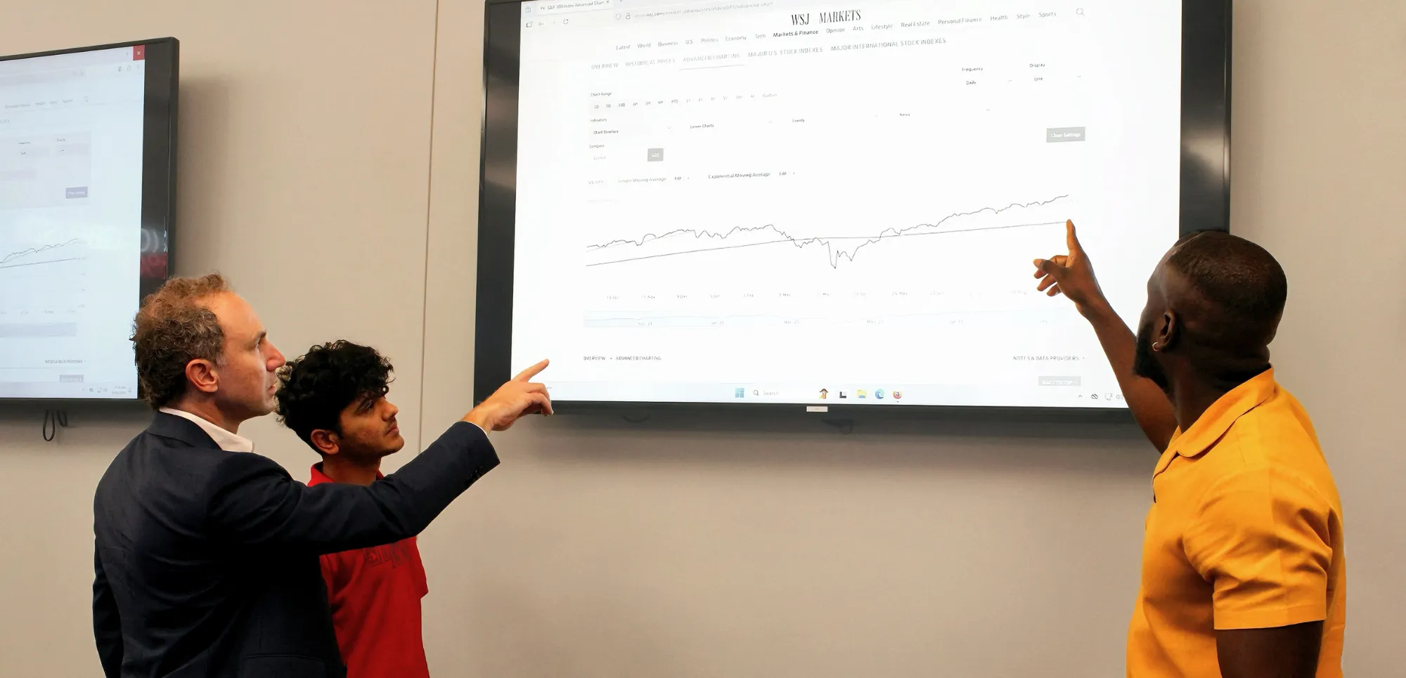 Dr. Hill and students analyzing the wall street journal markets in class.