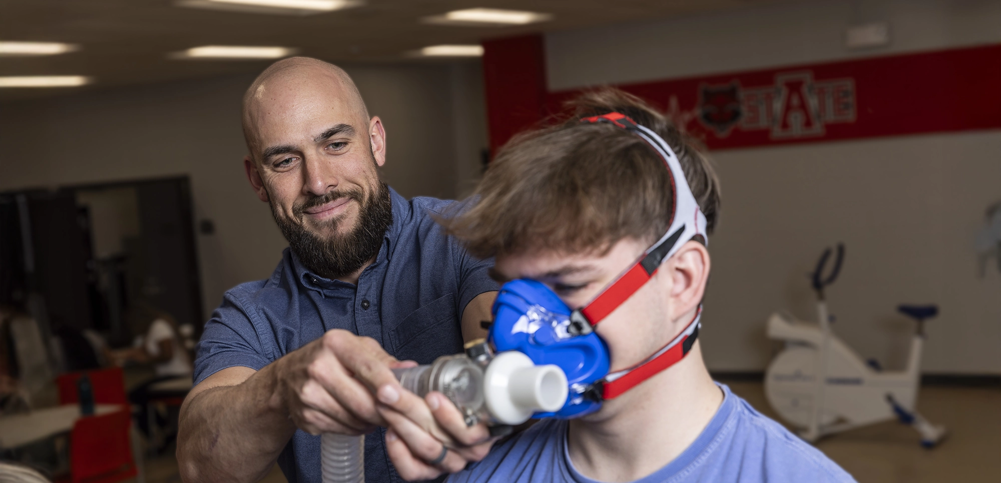 A professor recording a student's breathing as they exercise.