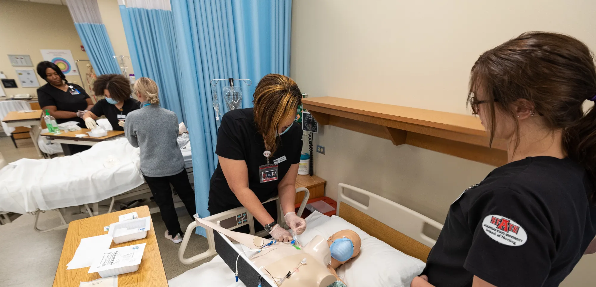 Students with teacher in a simulation hospital working on dummies.