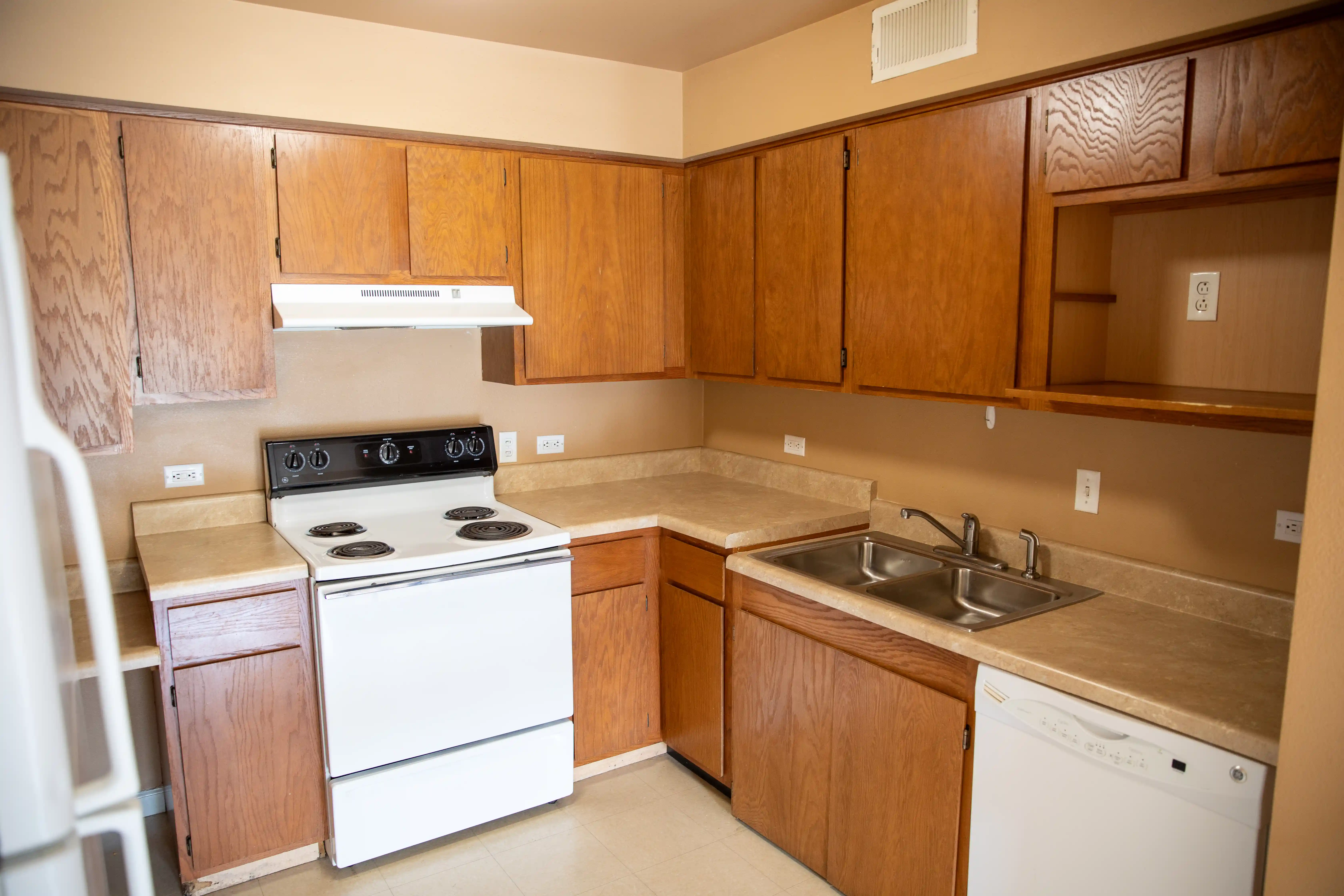 Kitchen with wooden cabinets, white appliances including stove, refrigerator, and dishwasher.