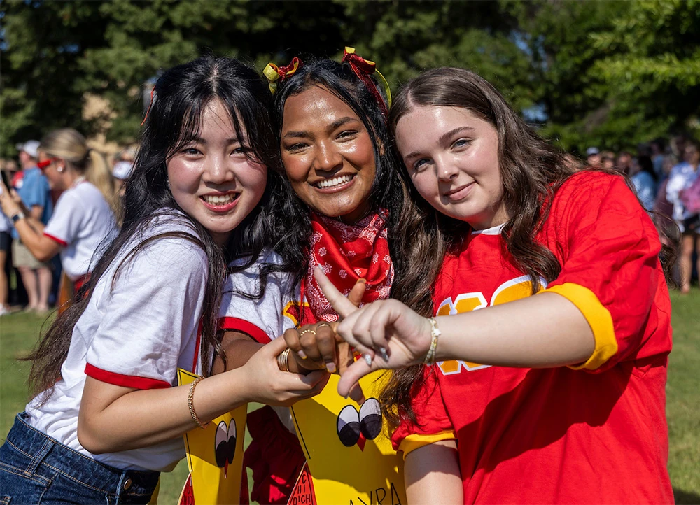 three smiling girls wearing colorful clothes on a sunny day