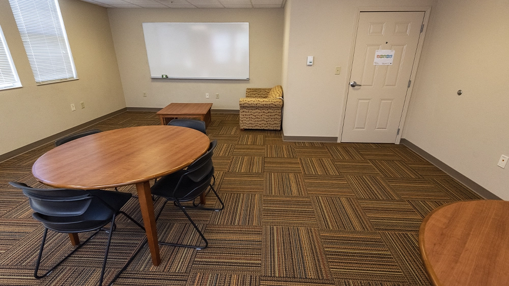 Study room with round tables, chairs, and whiteboard.