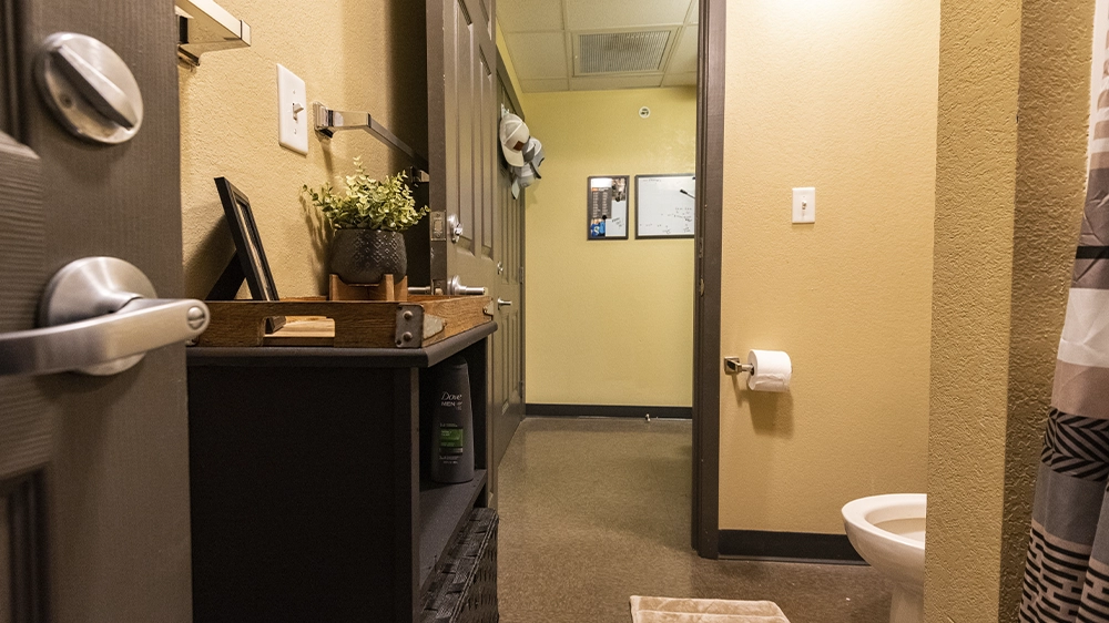 Bathroom with toilet, shelving unit, and shower curtain.