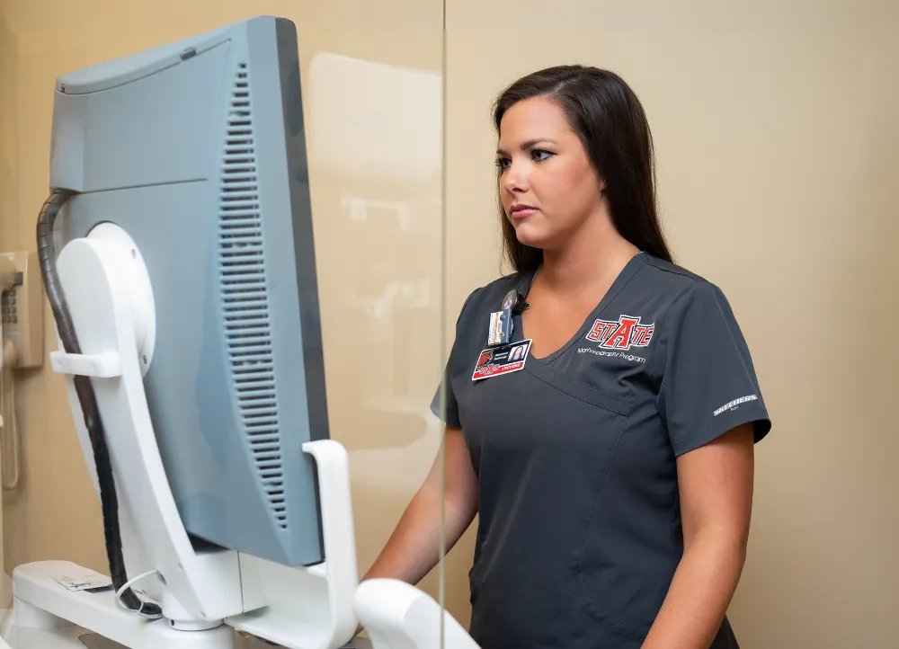 Radiology Student standing at a computer reading imaging results.