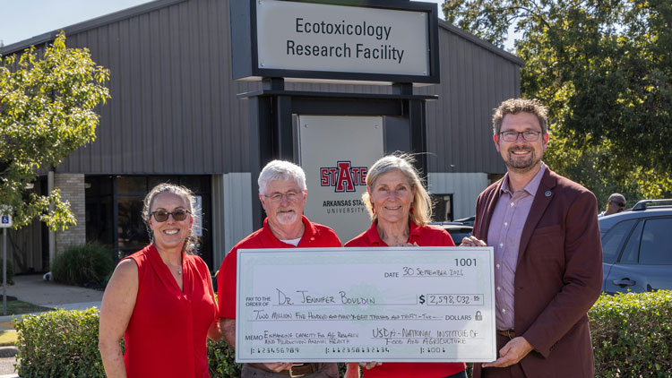 Standing in front of the Ecotoxicology Research Facility are, Dr. Heidi Banse, dean of the College of Veterinary Medicine, Dr. Bud Kennedy, interim dean of the College of Agriculture, and Dr. Jennifer Bouldin, who will lead the facility and research infrastructure improvements working across three academic colleges. They were presented with the “big check” by Dr. Travis Marsico.