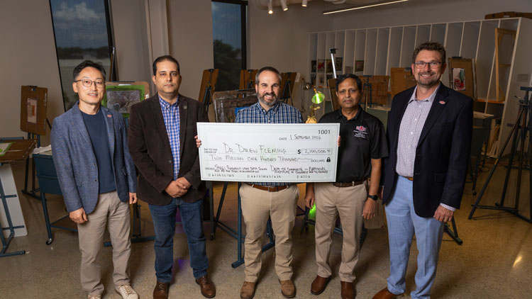 Group of men standing holding a big check