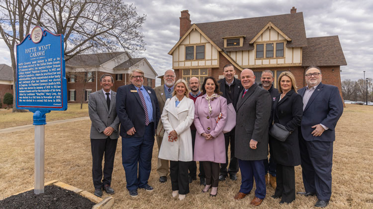 a group stands outside of the V.C. Kays house next to a historical marker