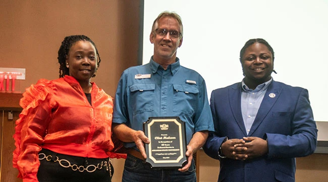 Clint Halcom (center), who is retiring at the conclusion of his 45-year career with A-State, is congratulated by Staff Senate representatives Angela Daniels and Benjamin Mack, chair of the Distinguished Performance Awards committee.