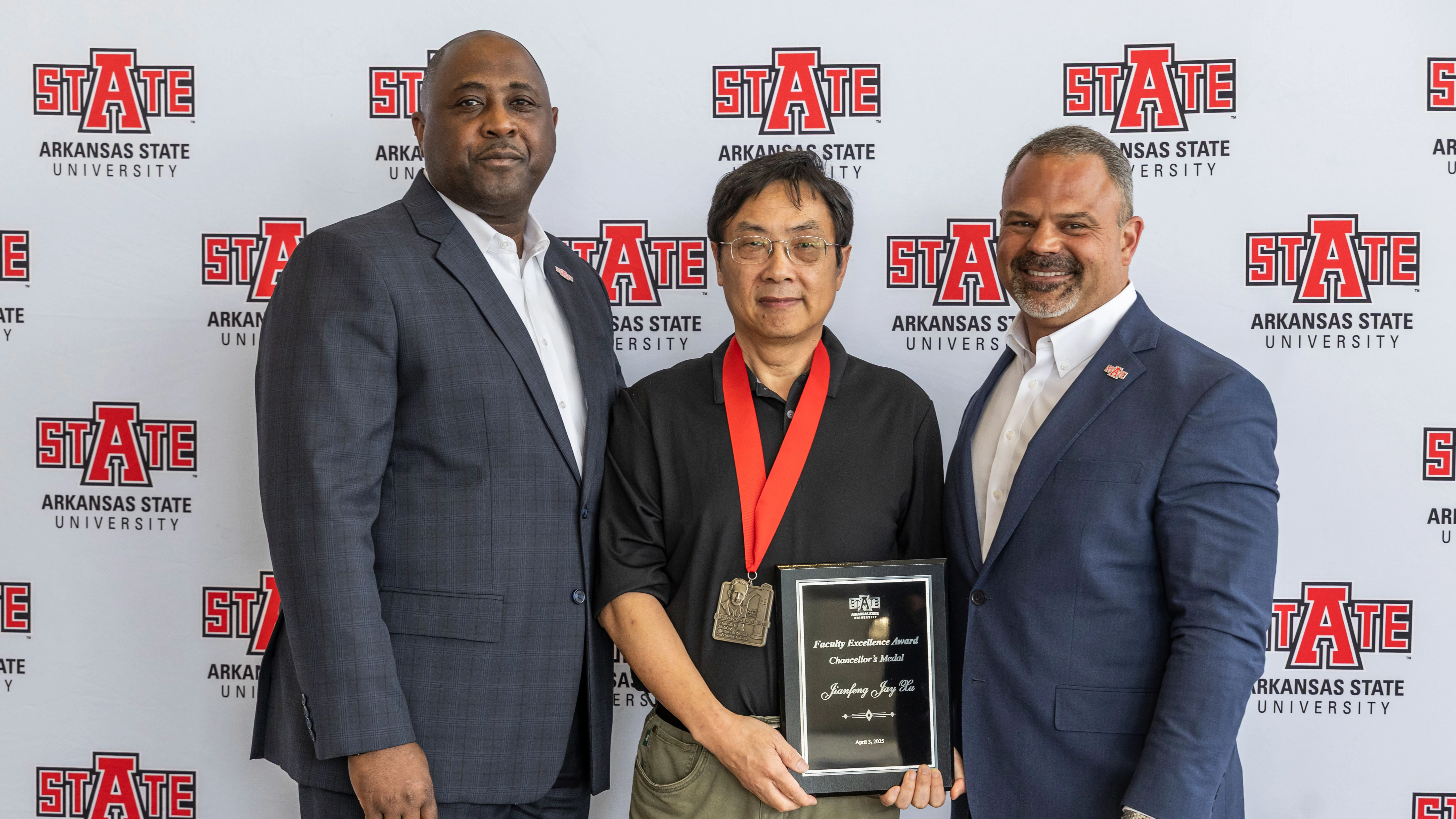Dr. Jianfeng (Jay) Xu (center), professor of biochemical engineering in the Arkansas Biosciences Institute and College of Agriculture, is congratulated by Dr. Calvin White Jr., executive vice chancellor and provost, and Chancellor Dr. Todd Shields.