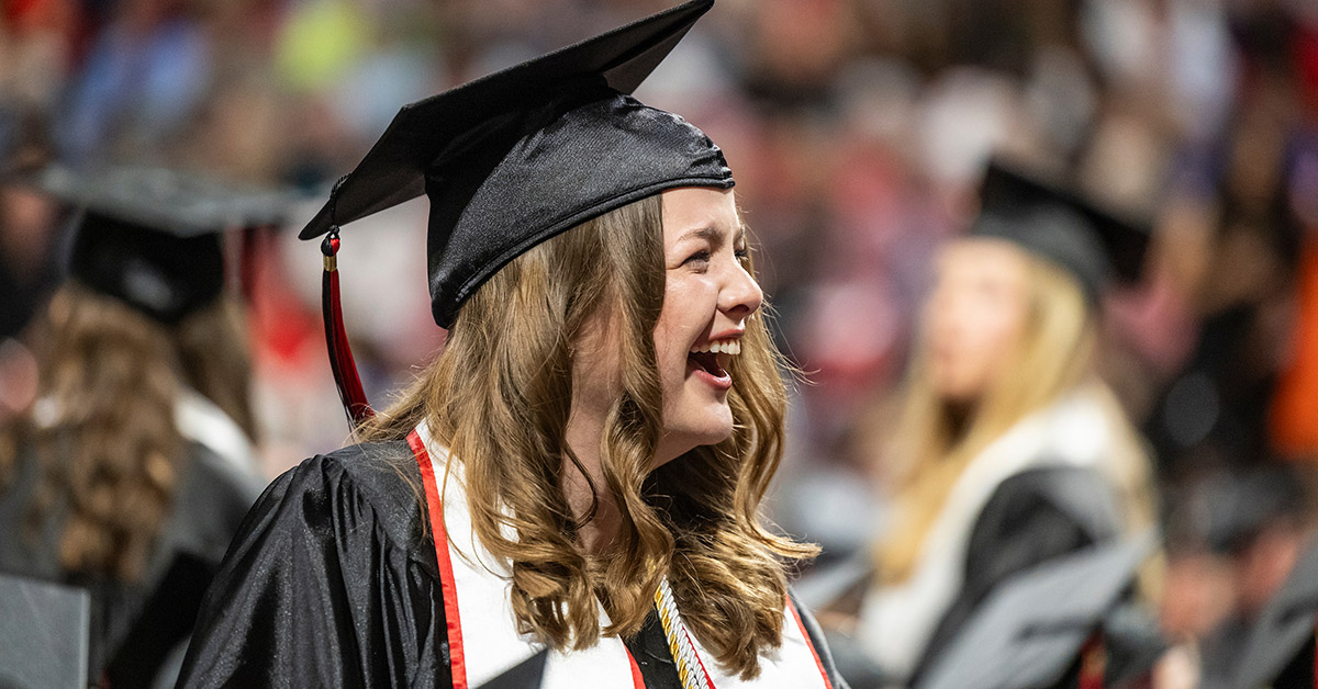A graduate smiles back at her family during the 2025 Spring Commencement