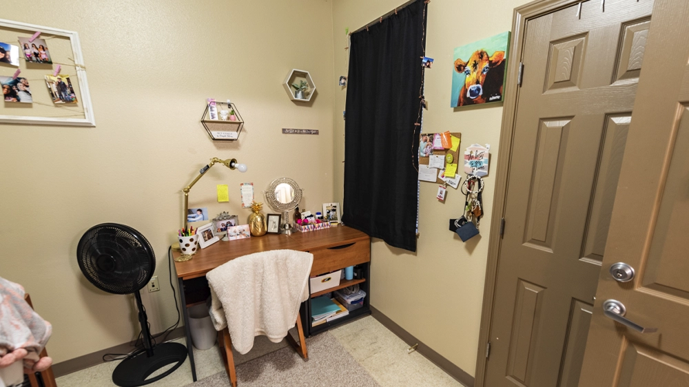Private bedroom in North Park Quads with desk, chair, and wall décor near entry door.