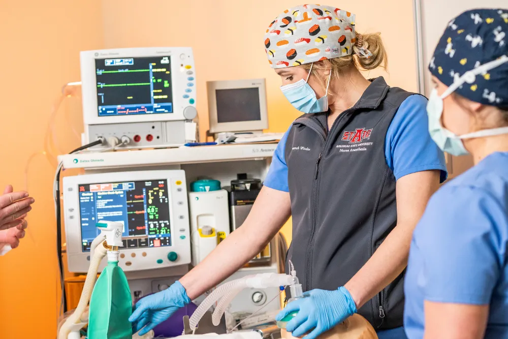 CRNA students in lab together working on intabating a dummy.