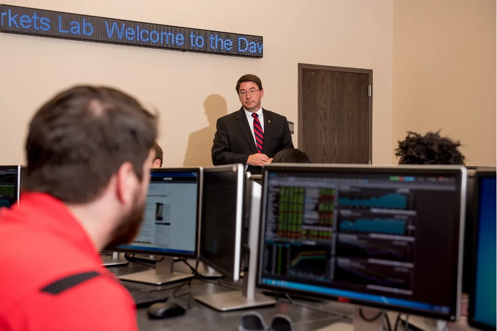 Accounting student and professor sitting at table with an A-State hoodie and laptop.