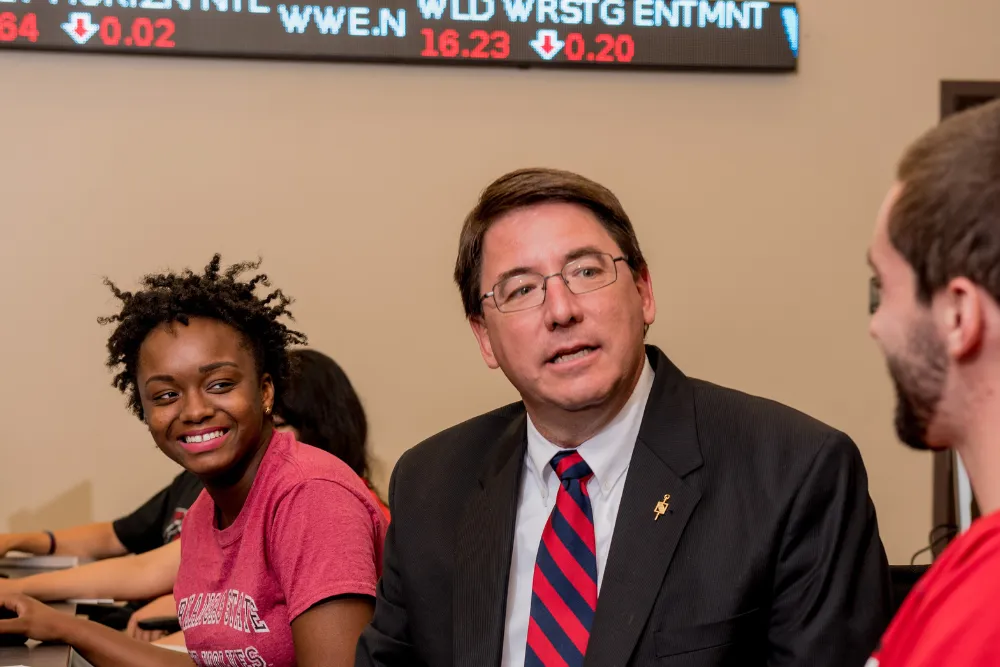 Accounting student and professor sitting at table with an A-State hoodie and laptop.