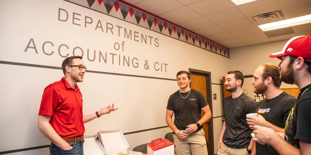 Accounting professor talking with students around boxes of donuts