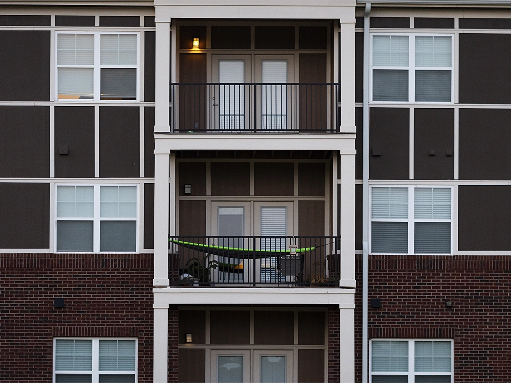 Close-up of three stacked apartment balconies at Pack Place, showing black railings, double doors, and a hammock on the middle balcony.