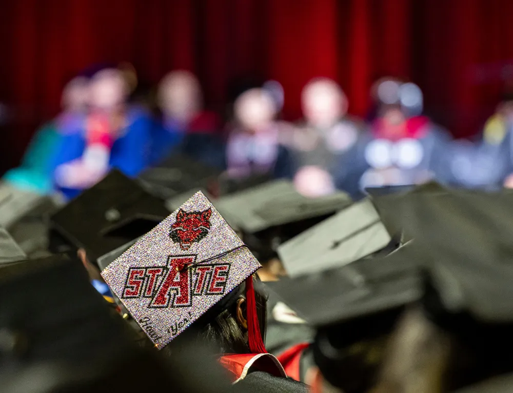 Three students posing with the HOWL sculpture on campus.